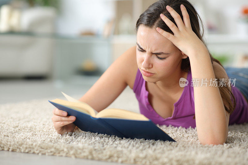 悲伤的女人在家里的地毯上读纸质书