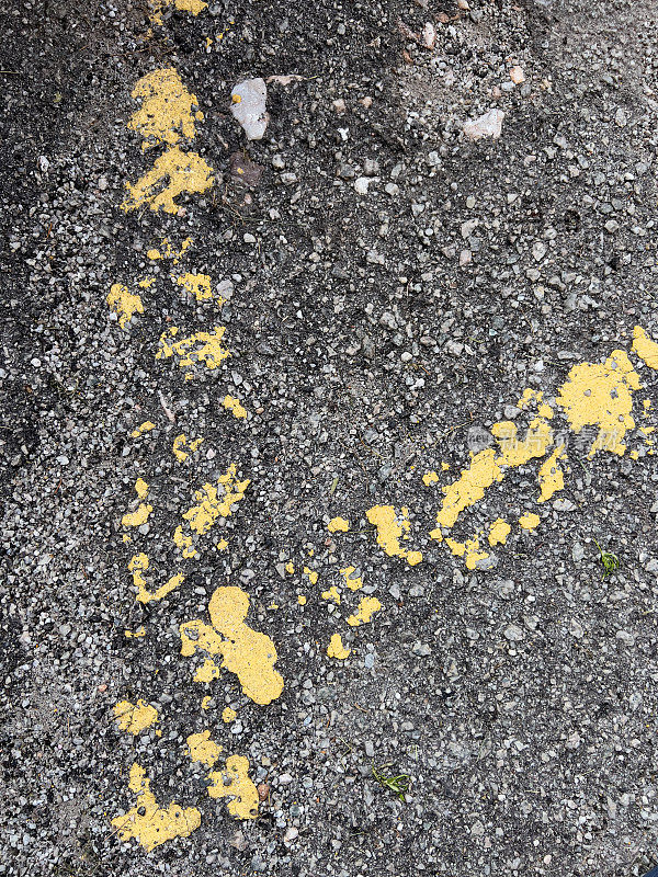 城市磨损的本质，在有纹理的沥青表面上表现出黄色道路标志油漆的残余。
