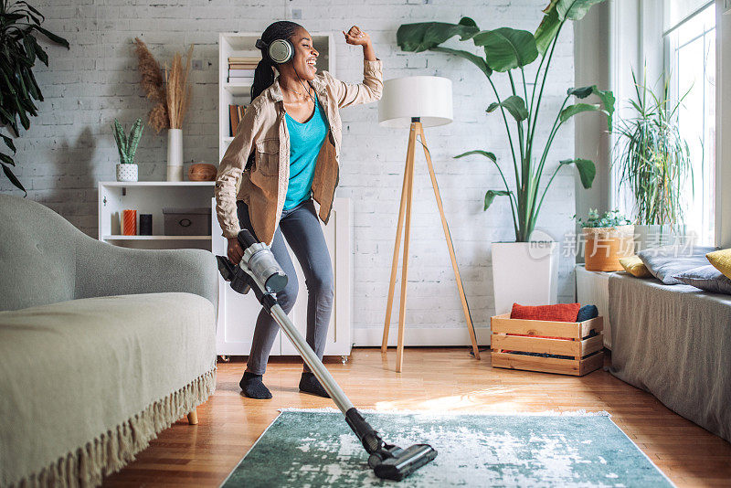 在现代家庭中，女人用吸尘器打扫客厅