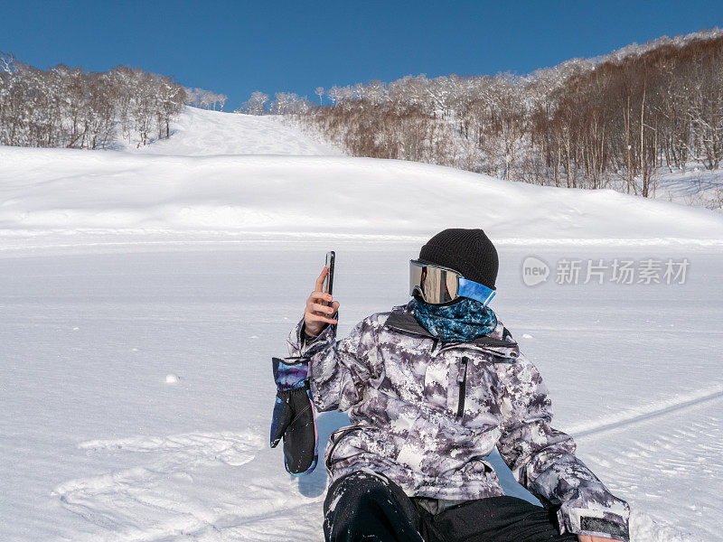 冬季滑雪坡道上，少年滑板运动员在拍照