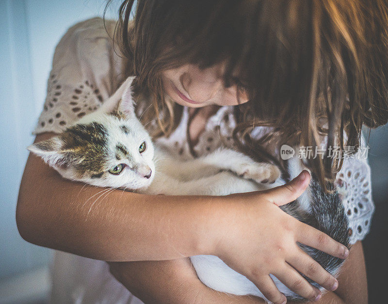 孩子喜欢她的宠物小猫，女孩依偎着她的猫伴侣，友谊，童年和动物