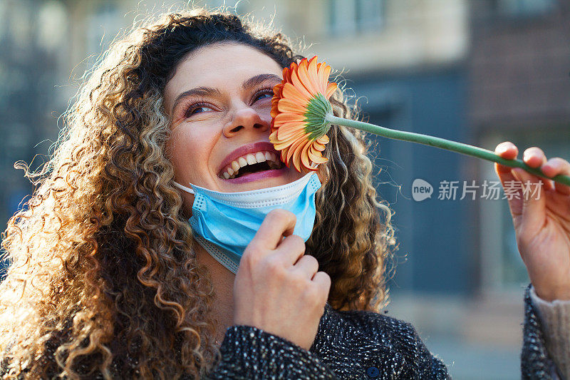 戴着面膜的年轻女子正在闻着花