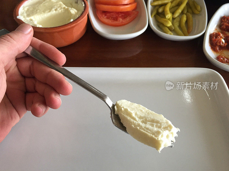 吃酸奶，酸奶放在叉子上，开胃菜放在餐桌上
