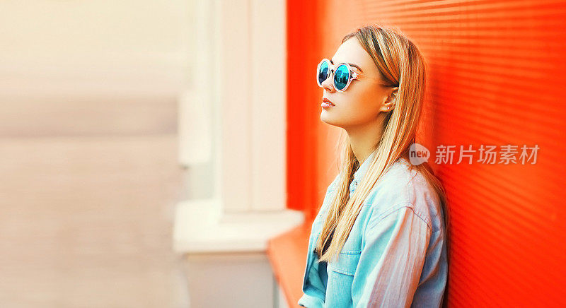 夏天的肖像美丽的金发女郎戴着太阳镜，衬衫在城市