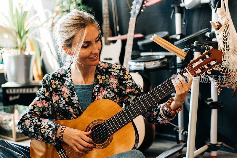 一个快乐快乐的女人弹原声吉他的肖像。