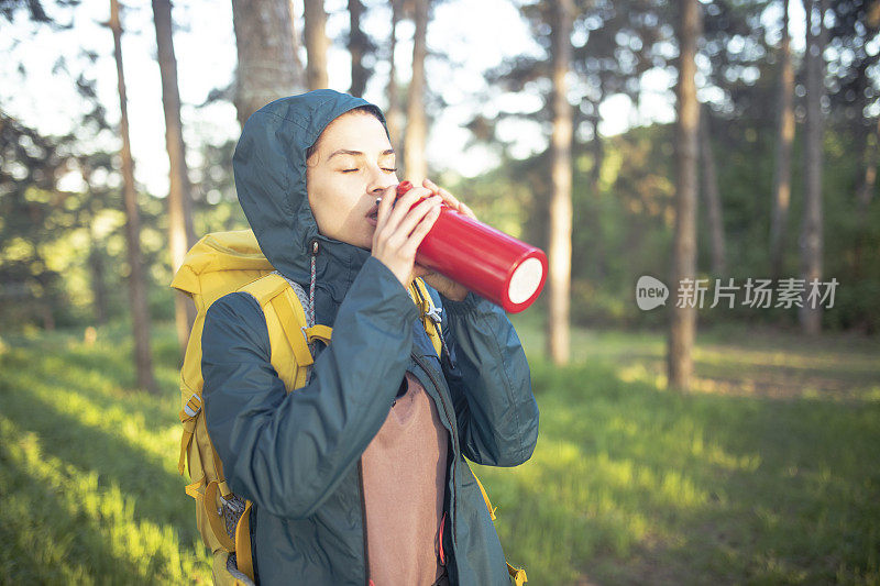 女人在树林里走了很长一段艰苦的路后，闭着眼睛喝水。