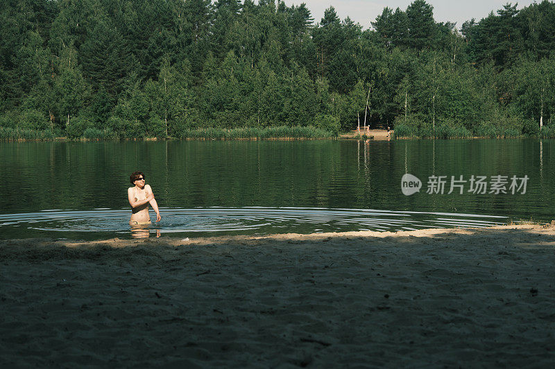 一个女人正在森林里的湖里游泳