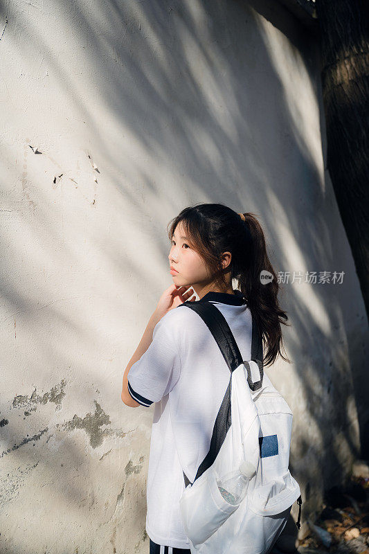 亚洲女孩背着书包在阳光下回家