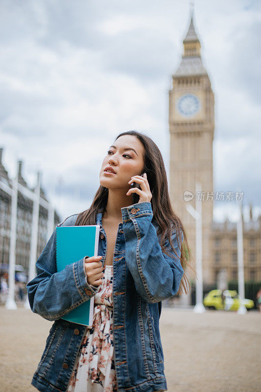快乐的亚洲女学生在伦敦使用电话