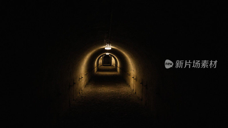 防空洞的一条长长的黑暗隧道，隧道的尽头有一盏灯。战时的防空洞。