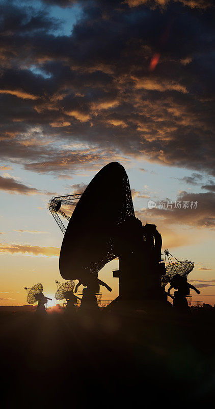 在日落的天空下，射电望远镜在田野上的剪影