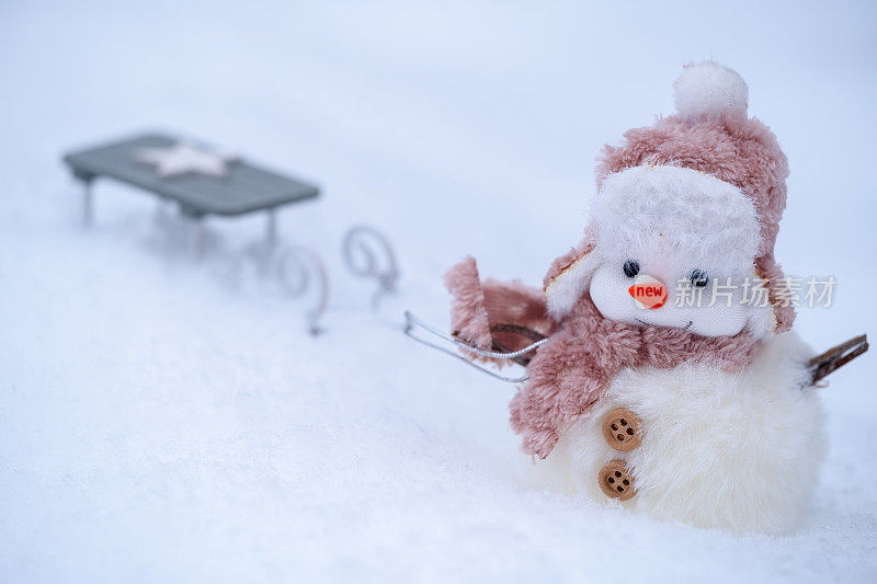 可爱的雪人在雪地上拉着雪橇。