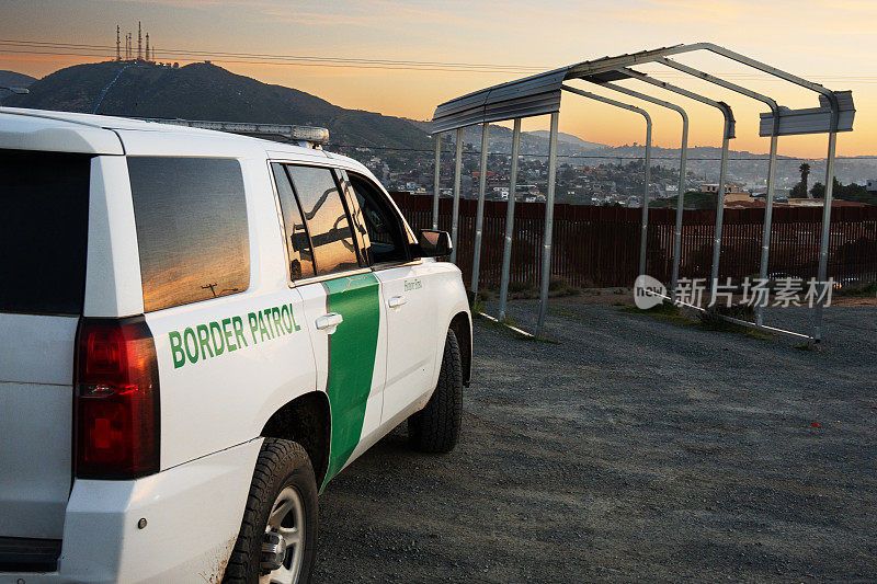 黄昏时分，美国边境巡逻车停在墨西哥和美国之间的蒂华纳附近的国际边境屏障上，对非法移民进行监视