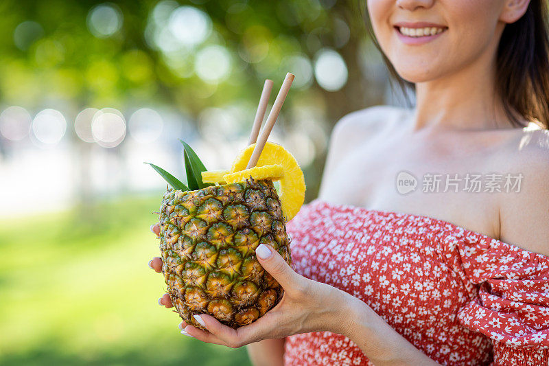 年轻女子喝着刚买的新鲜菠萝汁