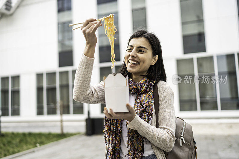 快乐的年轻女子享受着在户外吃意大利面