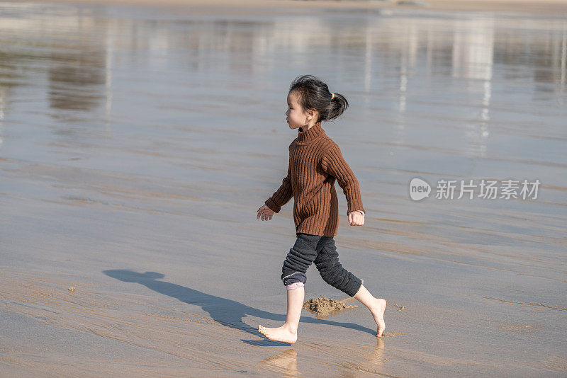一个亚洲女孩赤脚在沙滩上奔跑
