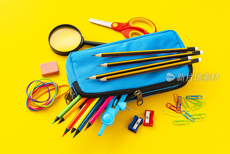 铅笔盒里装满了彩色的学习用品，以黄色为背景拍摄。