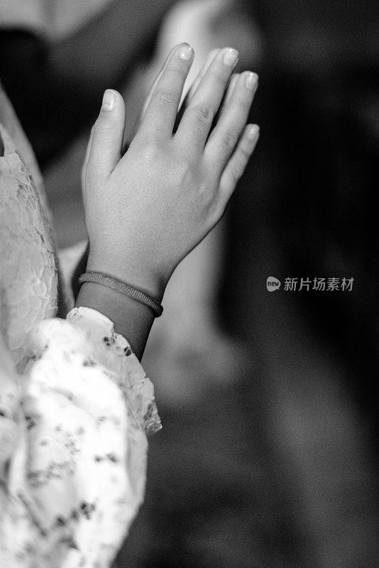 一个年轻女孩的灰度照片，她双手合十，摆出恭敬的姿势