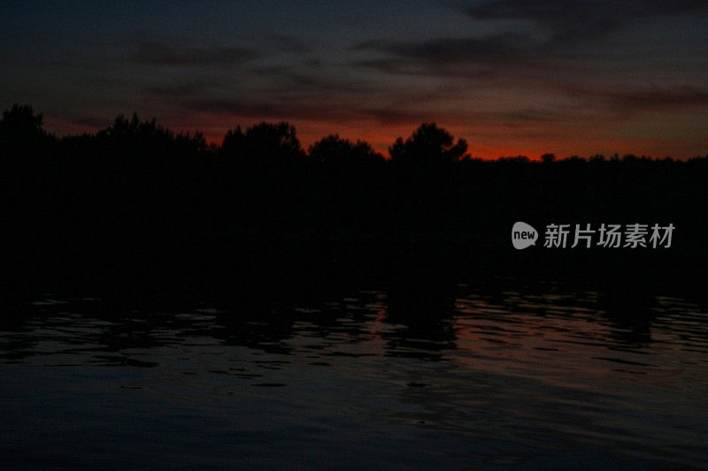 夕阳下的帆船，红色的天空映在水面上。