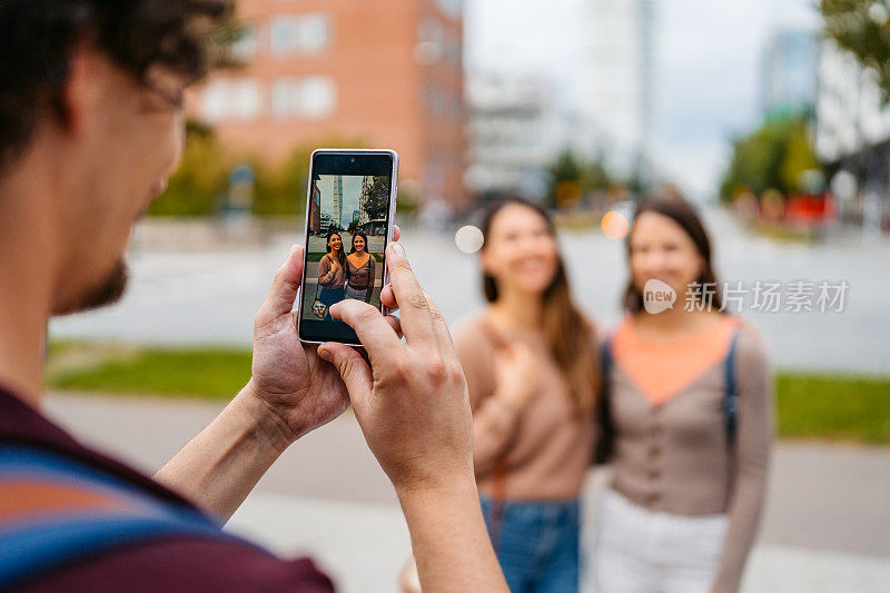 在瑞典马尔默，一个年轻人在街上给他的两个朋友拍照