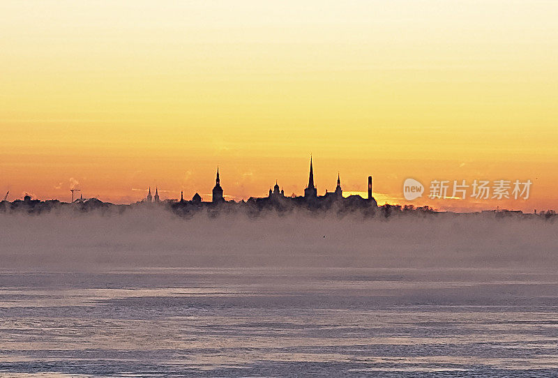 明亮的夕阳掠过海面，塔林老城的剪影在阳光的照耀下。