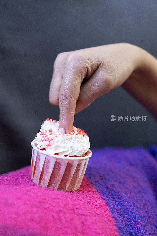 又馋又饿的女人用食指蘸甜点蛋糕。