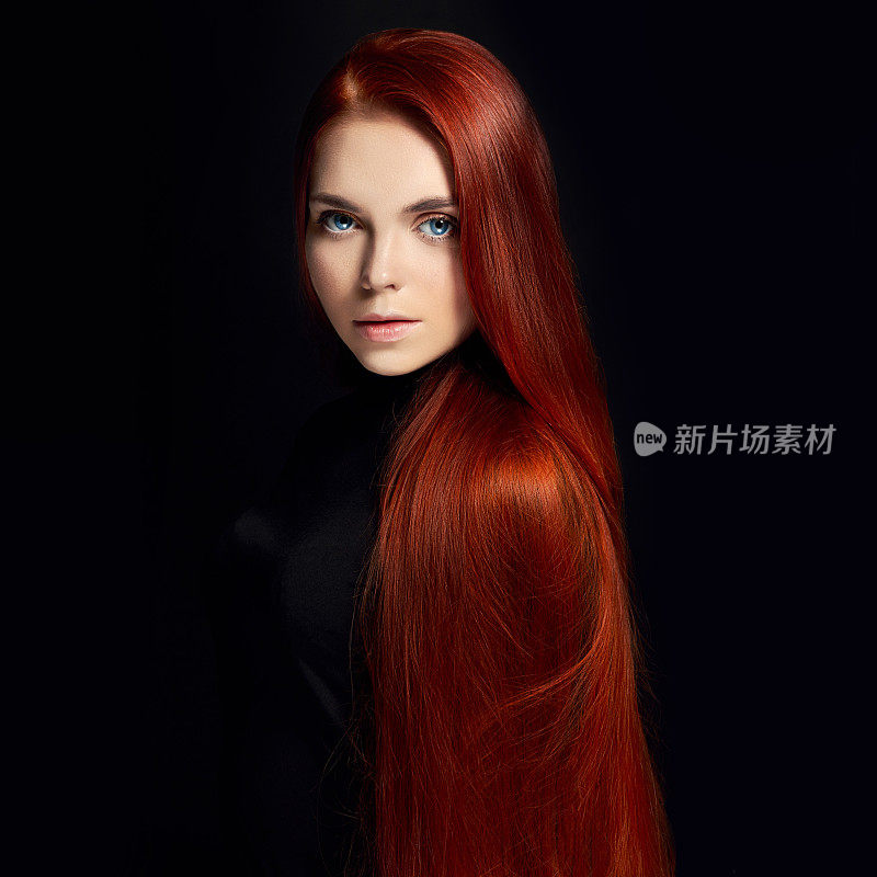 性感漂亮的长头发红发女孩。完美的女人肖像在黑色的背景。漂亮的头发和深邃的眼睛。自然美，清洁皮肤，面部护理和头发。强壮而浓密的头发