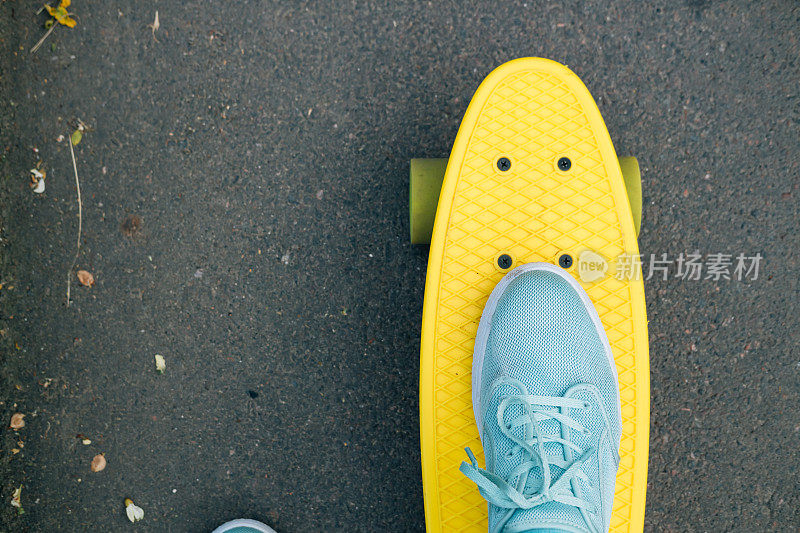 在黄色滑板上穿着蓝色运动鞋的女性脚