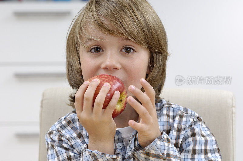 可爱的小男孩咬了一个红苹果