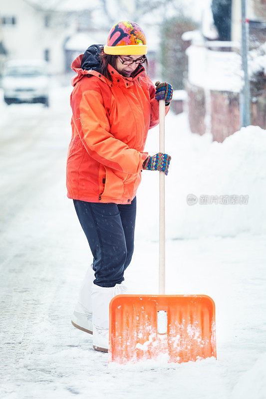 一个成熟的女人在清扫屋前的积雪