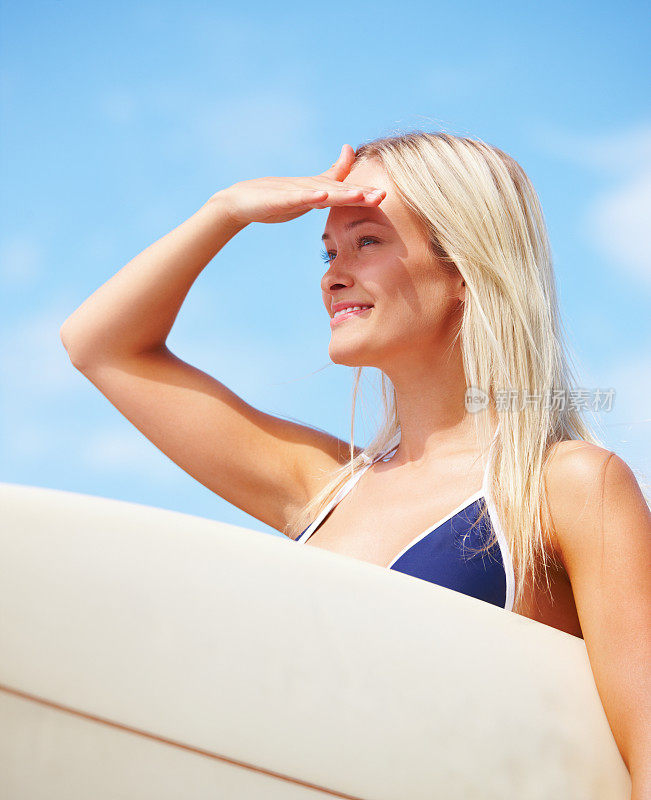 快乐的年轻女子，带着冲浪板和屏蔽的眼睛