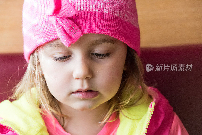 严肃的小女孩戴着一顶粉红色的帽子