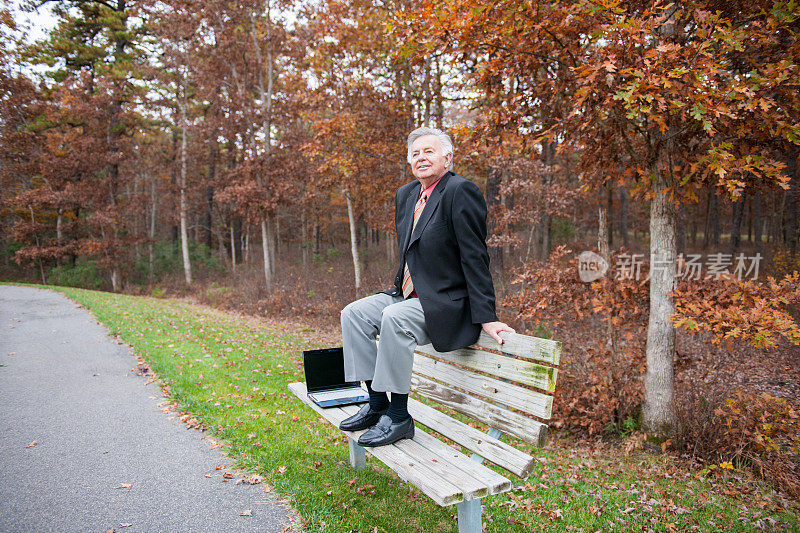 一个穿着考究的长者坐在公园的长椅上