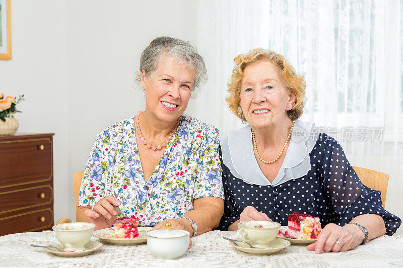 快乐的老女人一起吃蛋糕喝咖啡