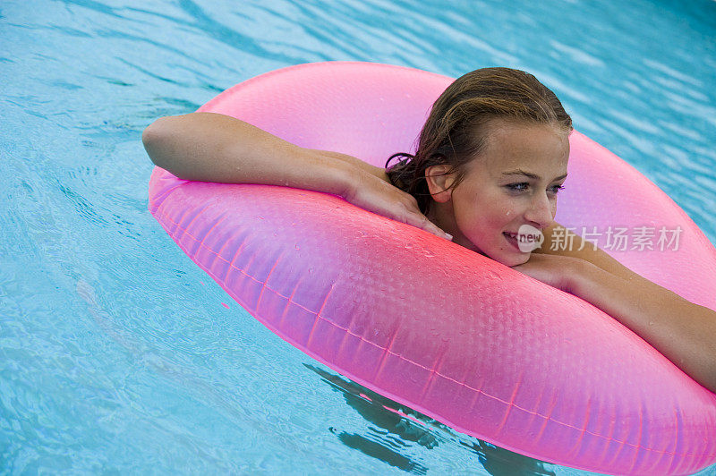 女孩漂浮在粉红色的游泳管里