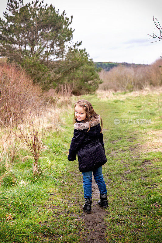 一个六岁的小女孩走在乡间小路上