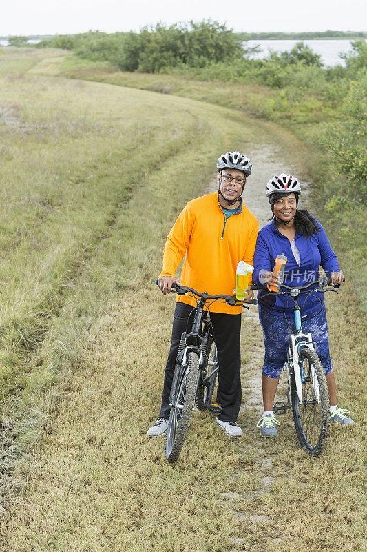 一对非裔美国夫妇，骑着自行车，拿着水瓶