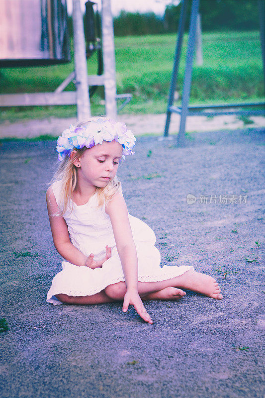 小女孩坐在砾石小路上