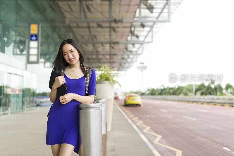 迷人的长发亚洲女人在机场候机厅外等候