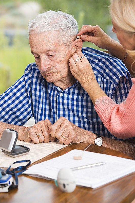 帮助老人调整助听器的护工