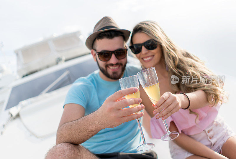 一对年轻夫妇在游艇上看着镜头敬酒