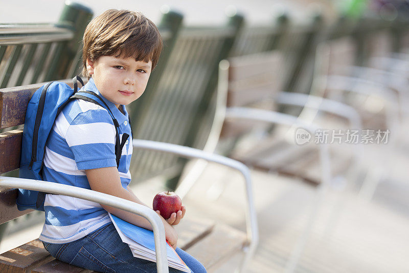 一个悲伤的男生坐在操场上的长凳上