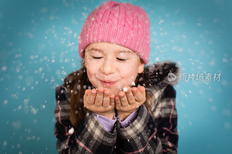 快乐的小女孩吹着一把雪