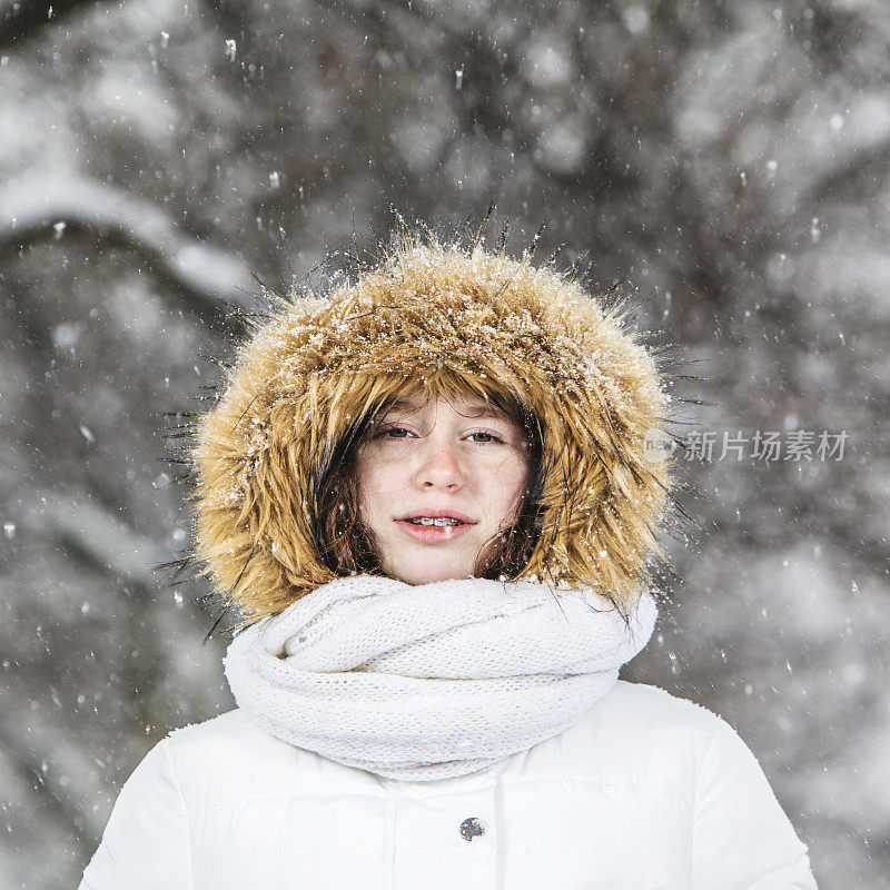 雪下穿着白色夹克的漂亮少女