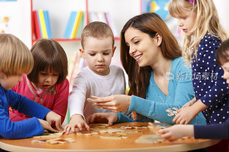 幼儿园老师和学龄前儿童在玩拼图游戏