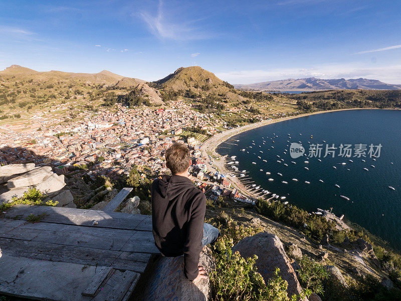 一个年轻人坐在秘鲁的喀喀湖科帕卡巴纳市美丽的风景中