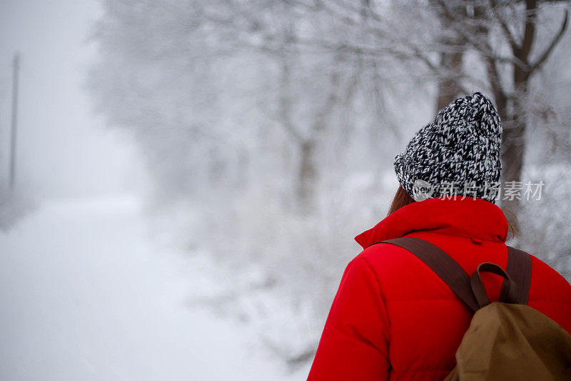 女徒步旅行者背包和雪鞋在雪地上的雪鞋