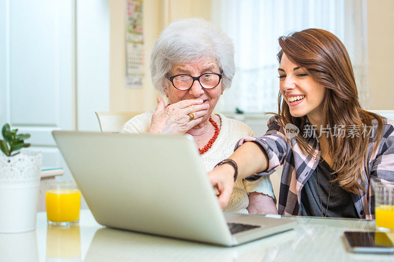 孙女指着电脑屏幕上的东西对着家里的奶奶。