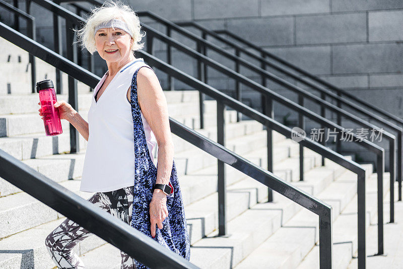 快乐的老妇人站在室外的楼梯上