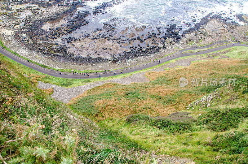 秋天的一天，人们沿着通往北爱尔兰大西洋海岸巨人堤道的小路行走